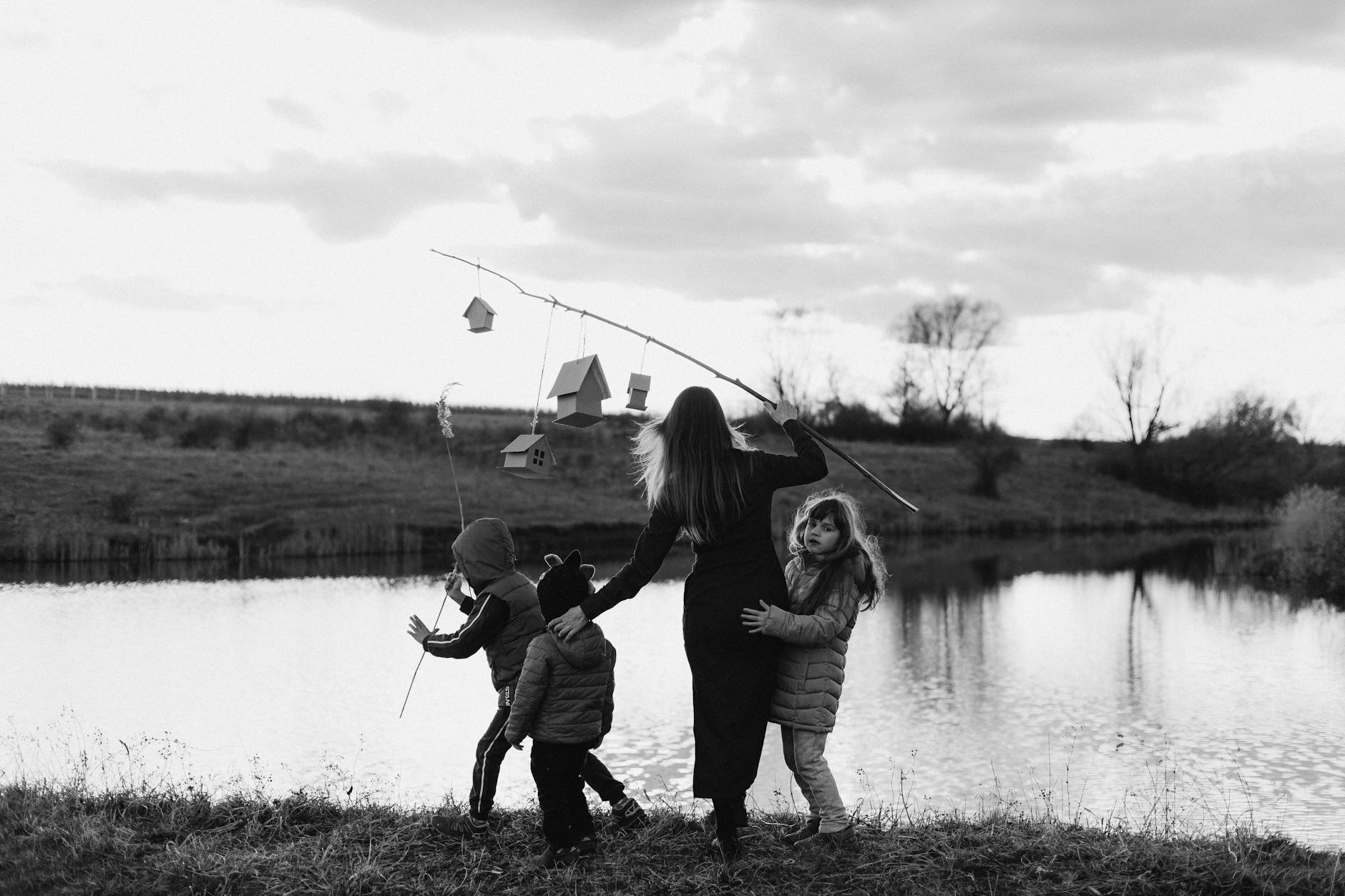 mother with fishing rod and children on lakeshore