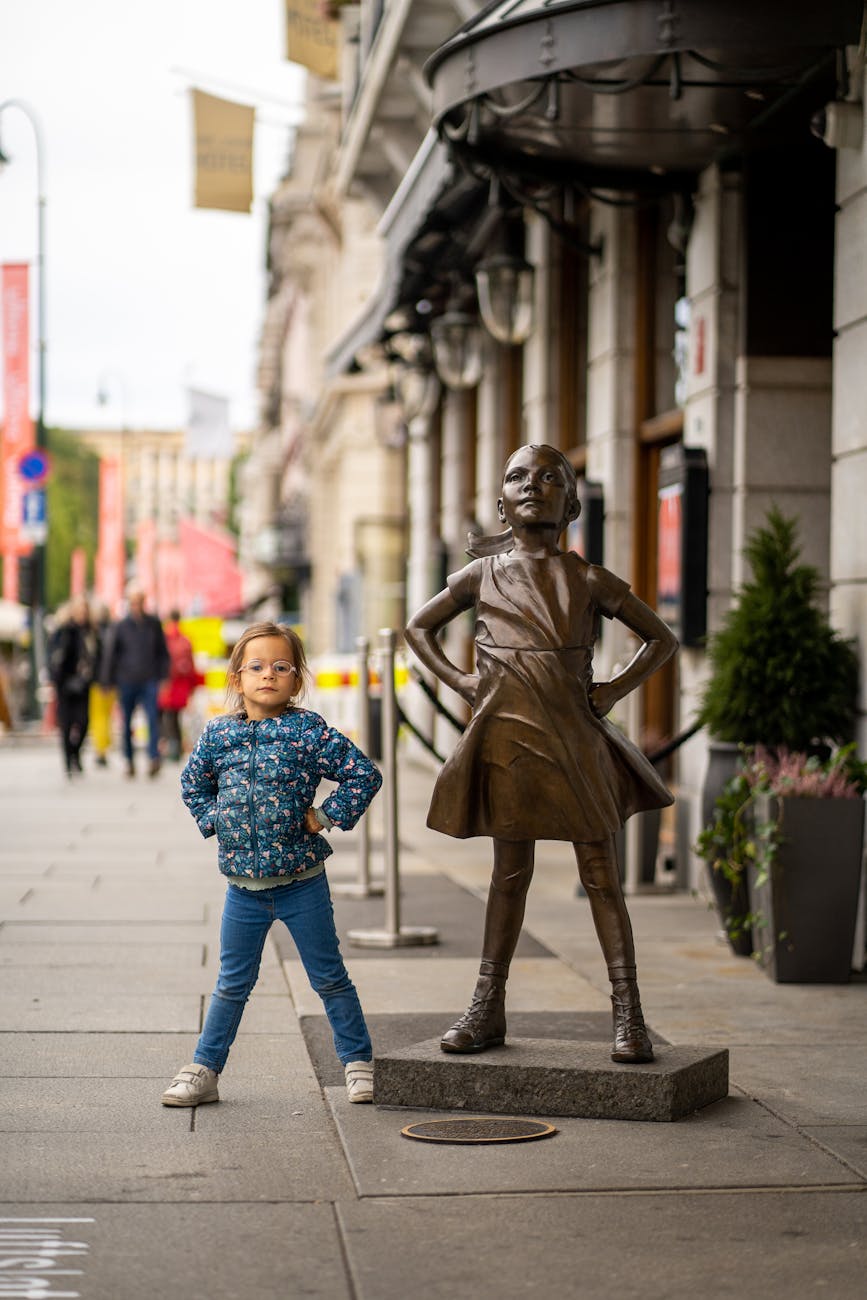 girl posing by the fearless girl statue in new york