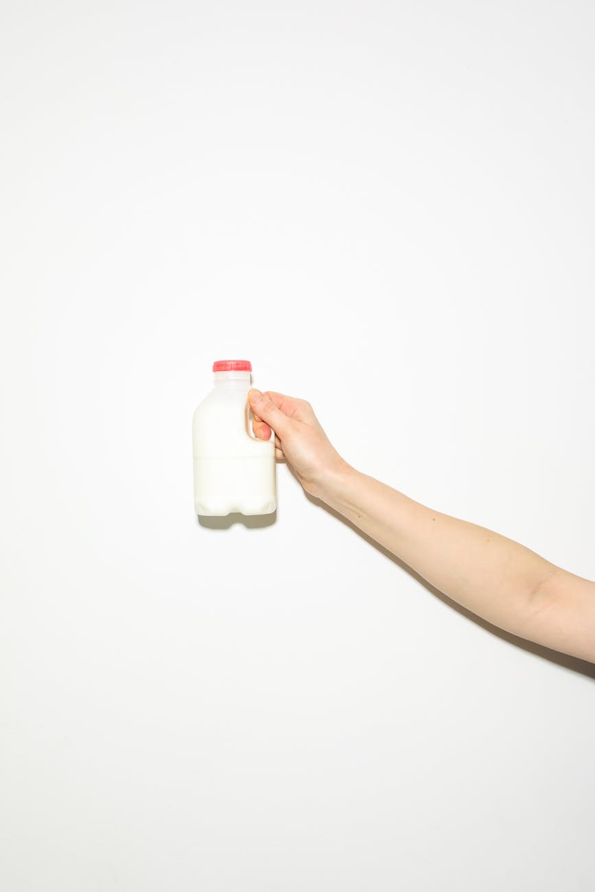 person holding white plastic bottle of milk