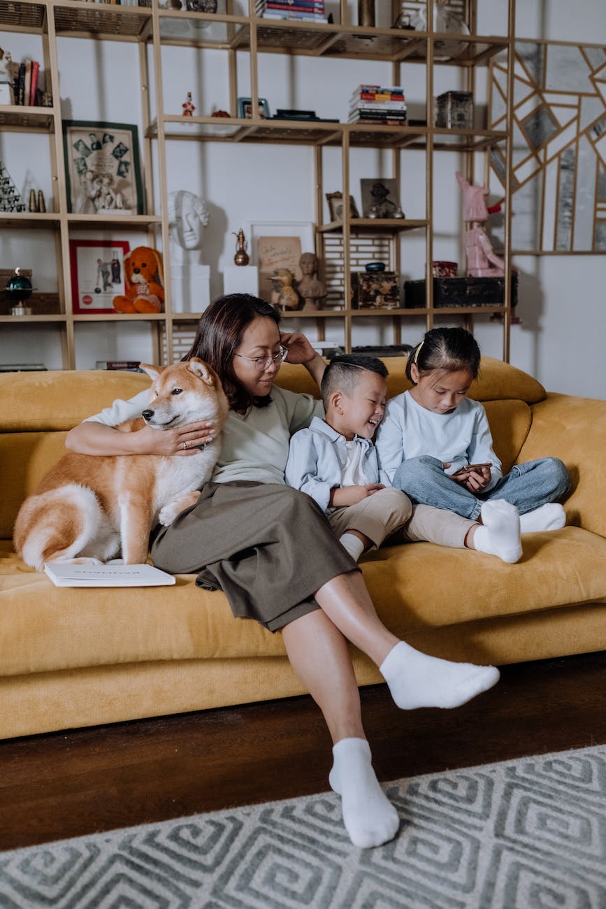 a mother sitting on the couch with her kids and their dog