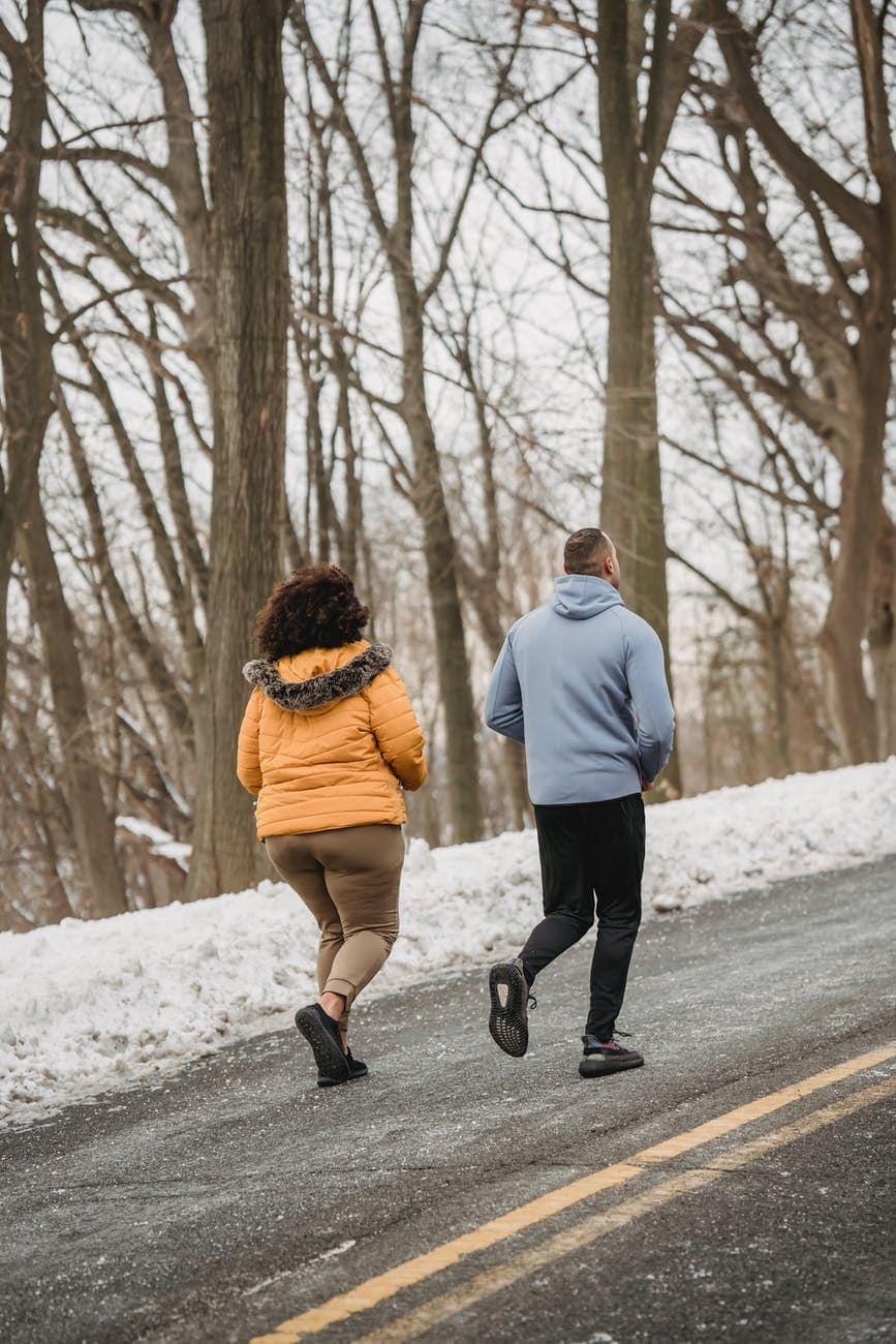 unrecognizable couple running in snowy park