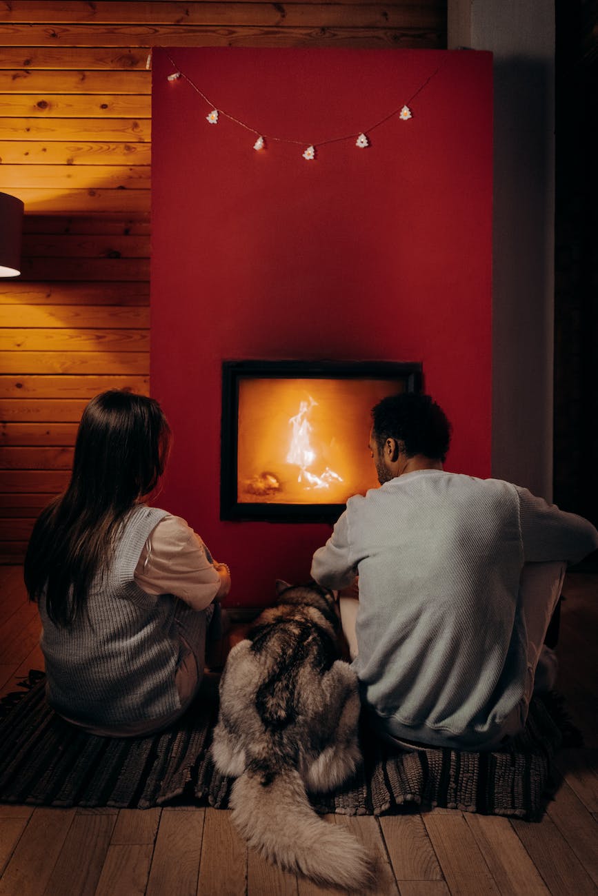 couple sitting near fireplace with their dog