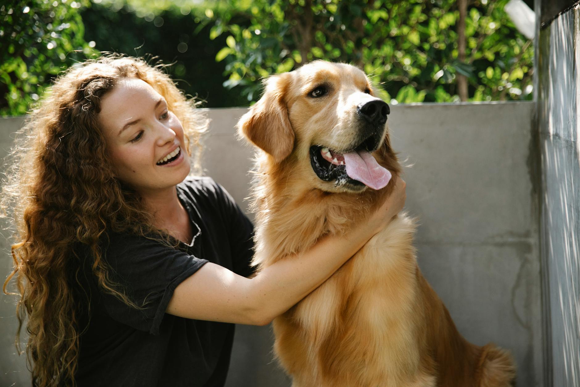 smiling female with dog near fence and plants